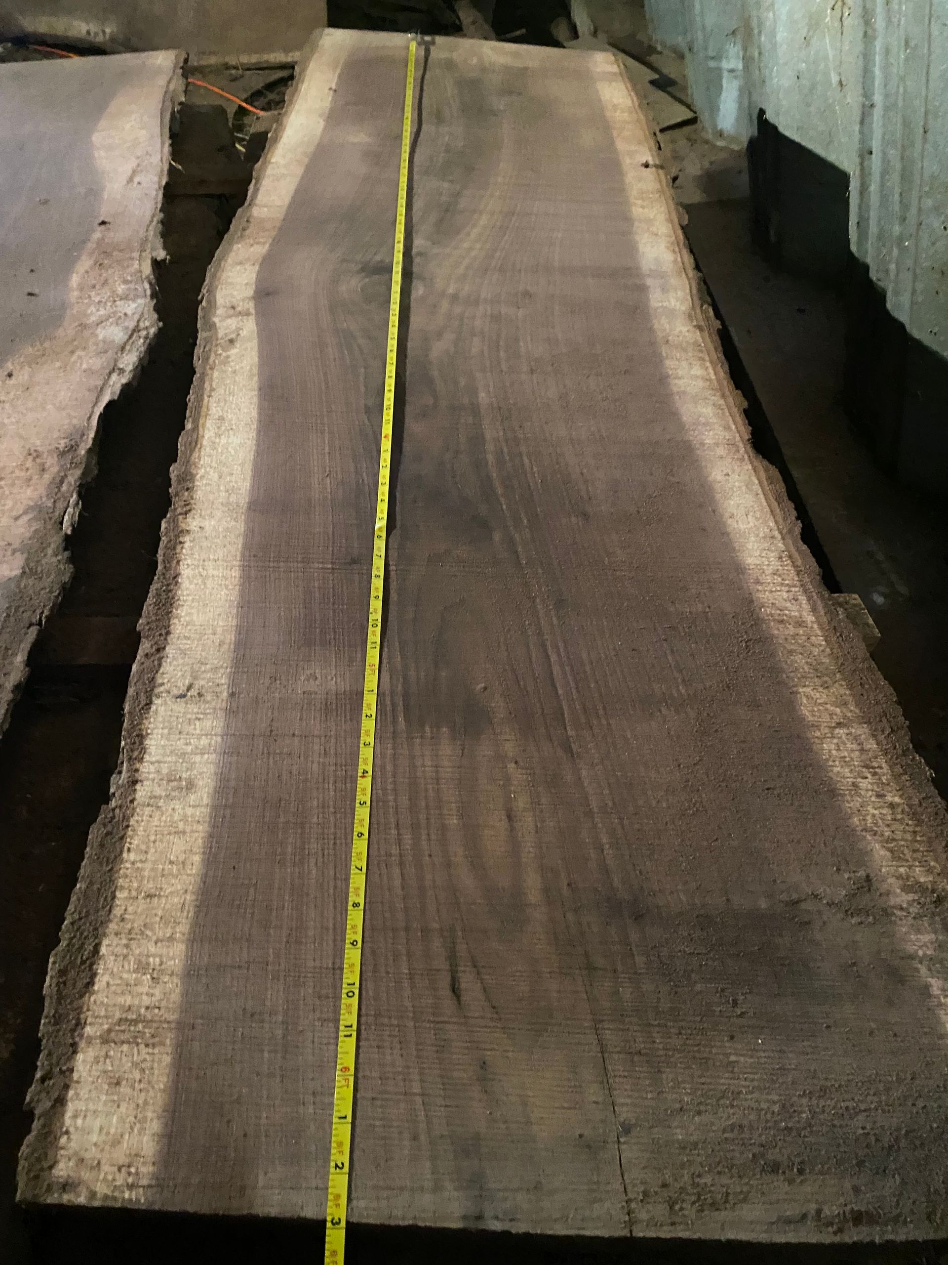 A long, dark wood slab with a yellow measuring tape running down its length.