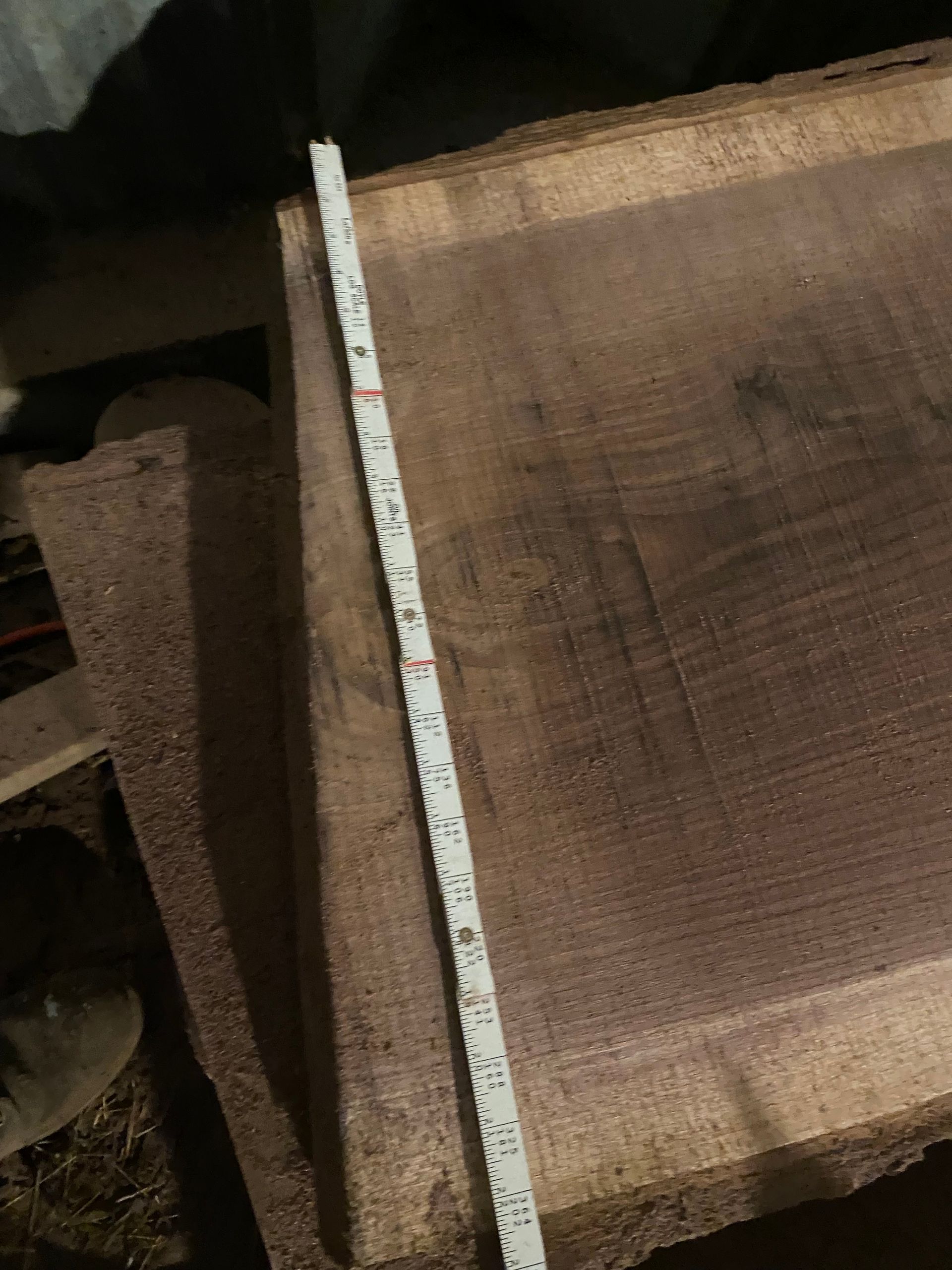 Tape measure on a dark wood slab, showing measurements.