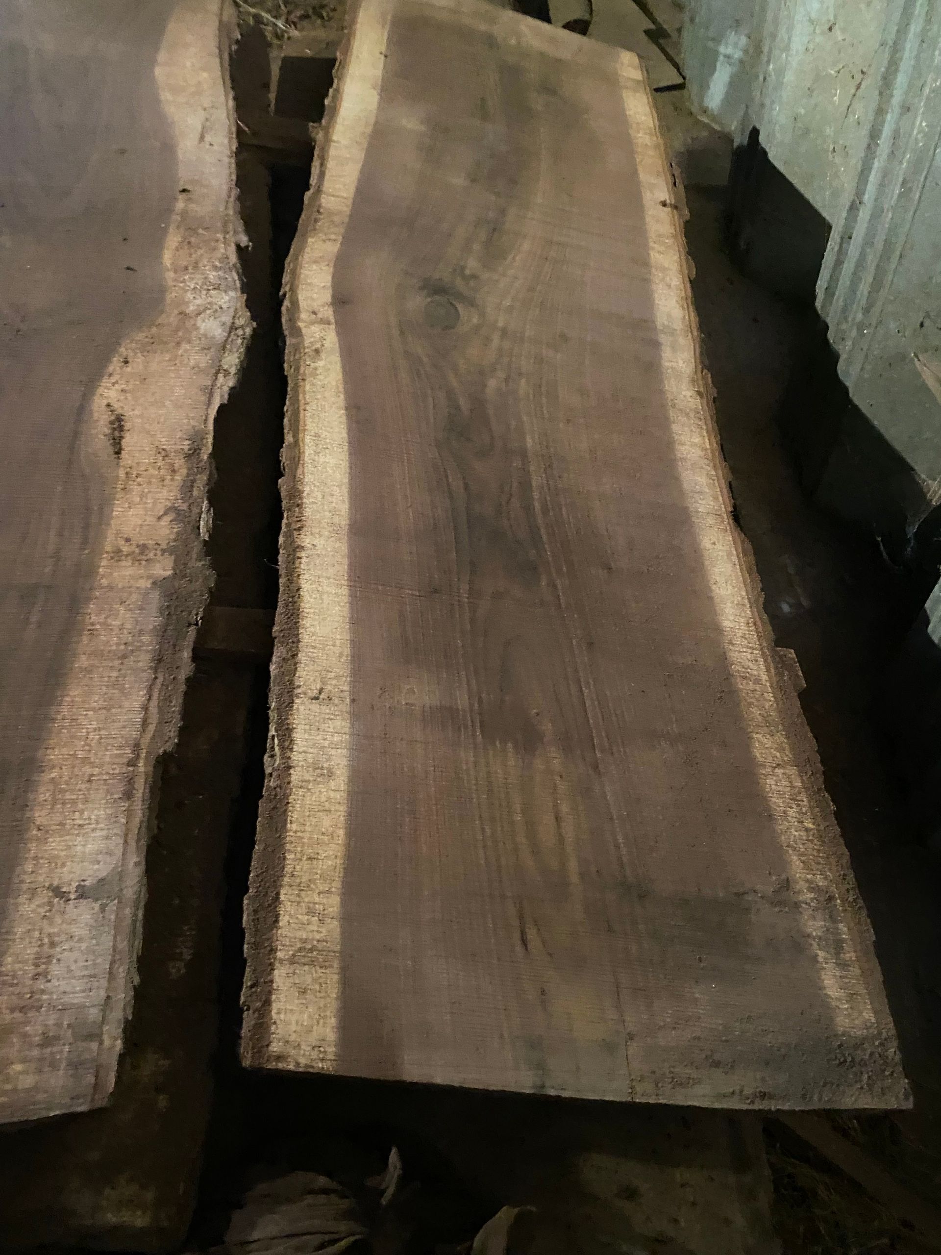 Dark wood slab with a light-colored live edge, lying on a dark surface.