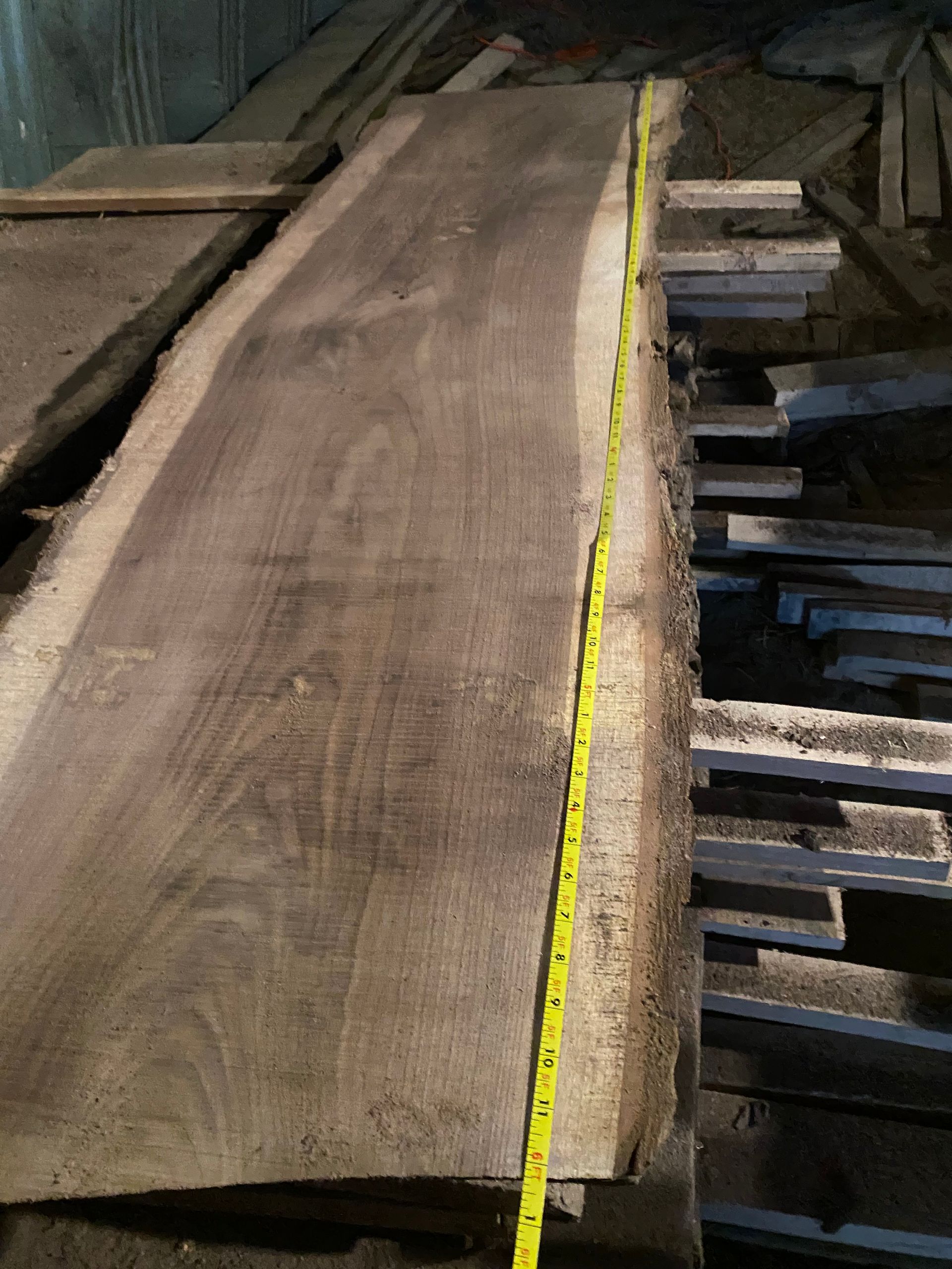 A large, gray wooden plank with a yellow tape measure, likely in a lumberyard.