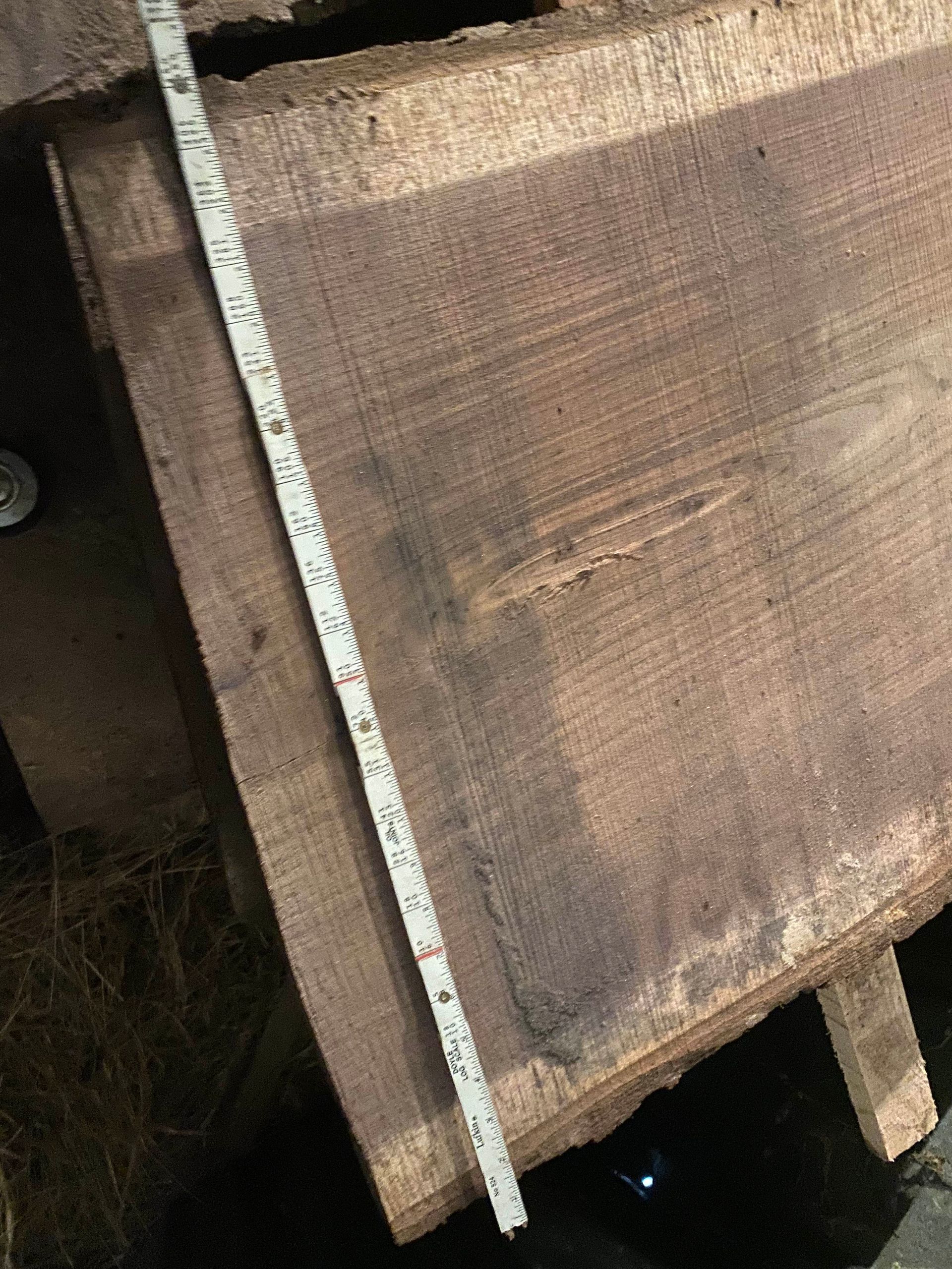 Wooden plank, partially visible, with a measuring tape placed alongside. Brown color.