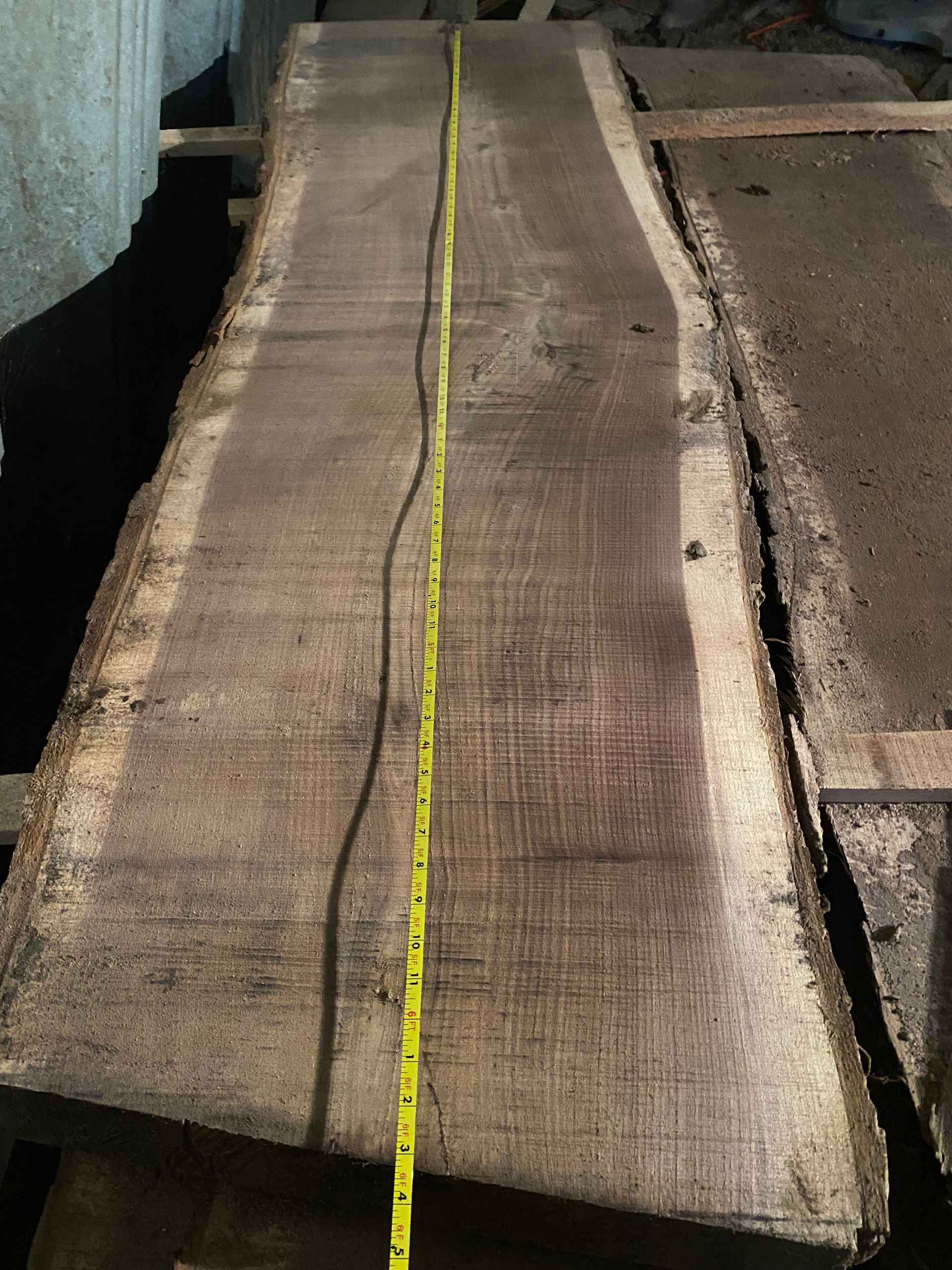 Wooden slab with a yellow measuring tape running its length.