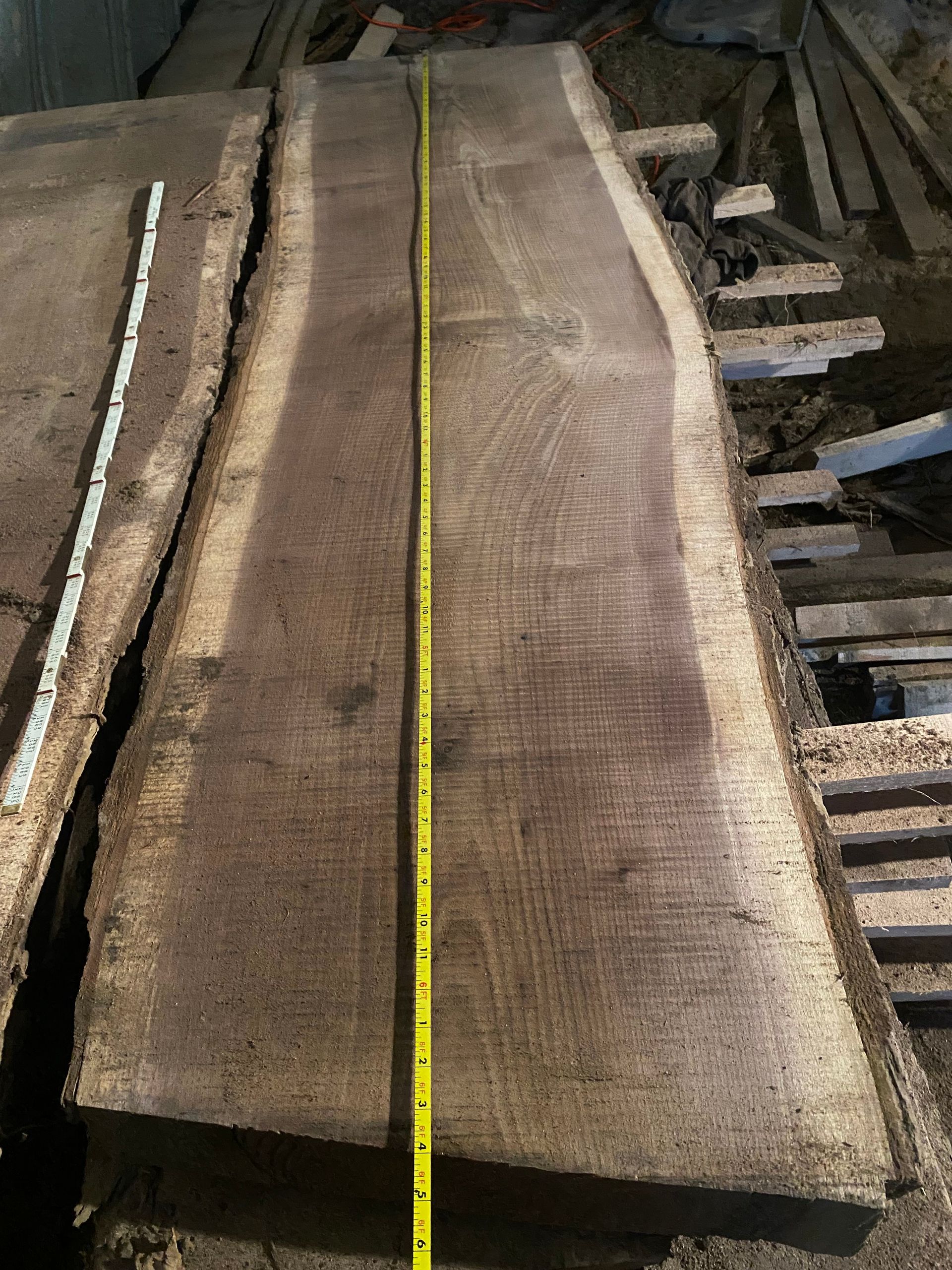 A long, brown wooden slab with a yellow measuring tape running down its length.