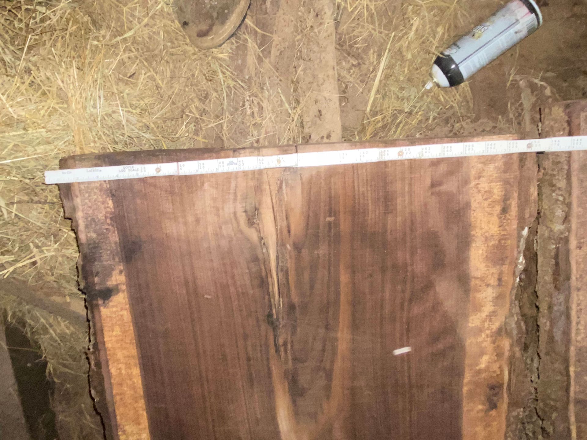 A dark brown wooden slab with a ruler laid across it, a can of spray adhesive is nearby.