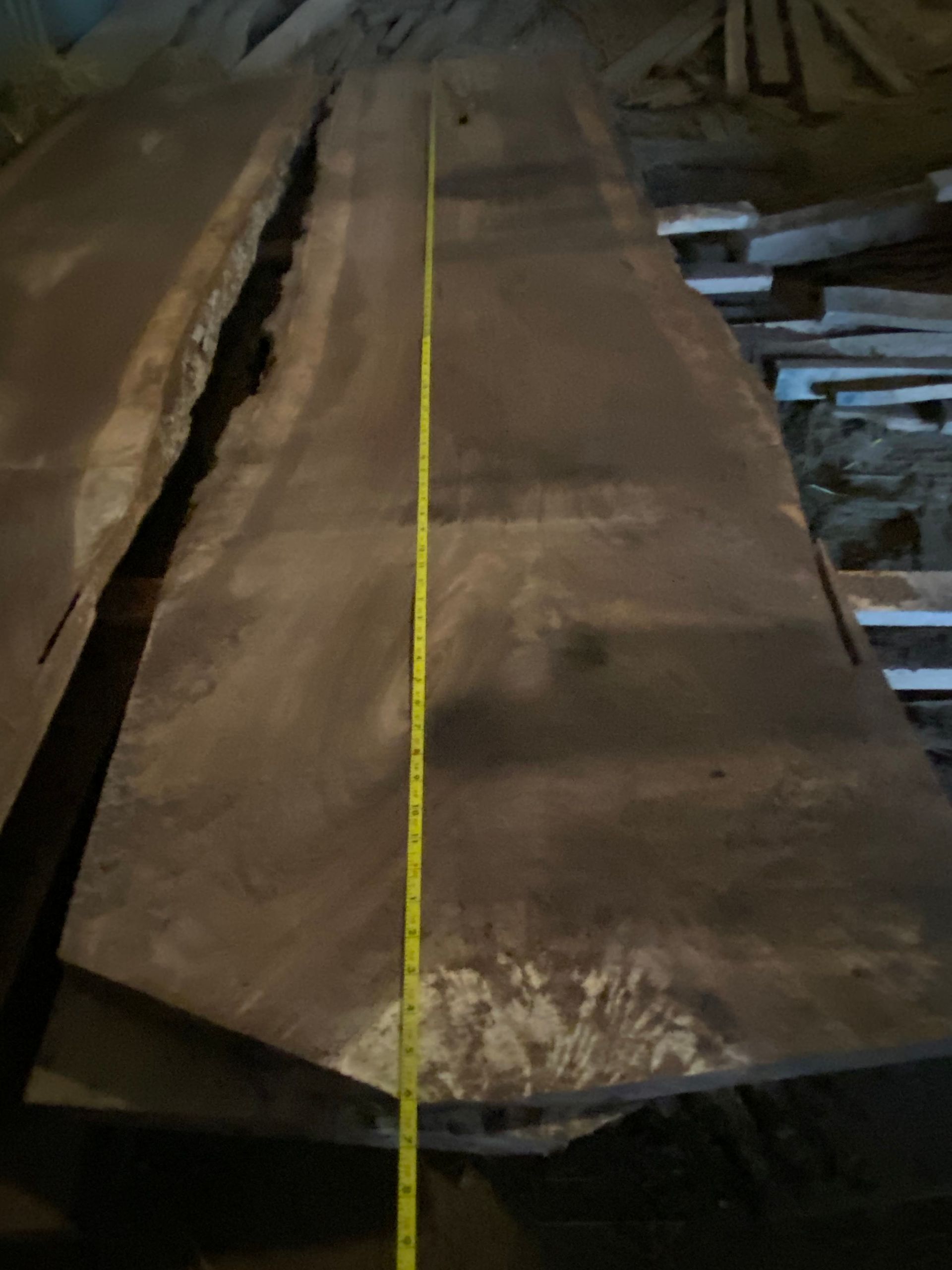 Large dark wood slab with a yellow tape measure running along its length.