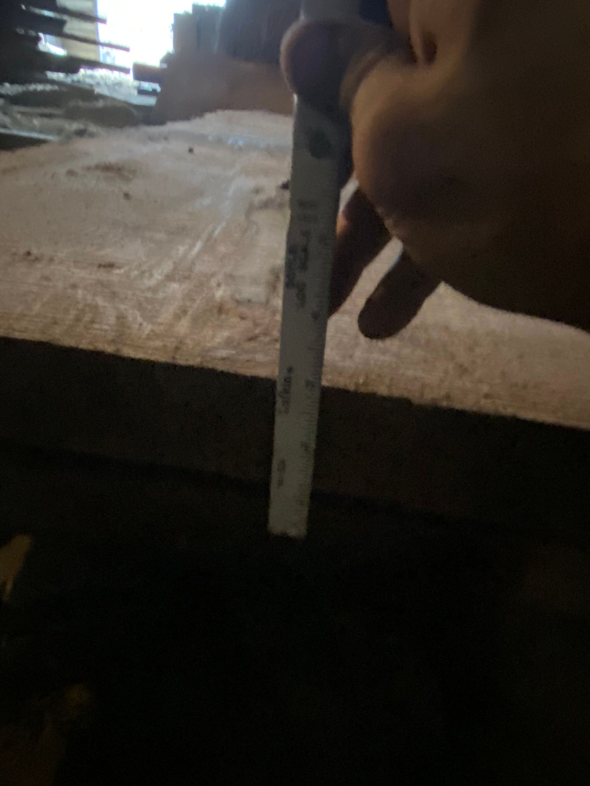 Person measuring a wooden surface with a ruler.