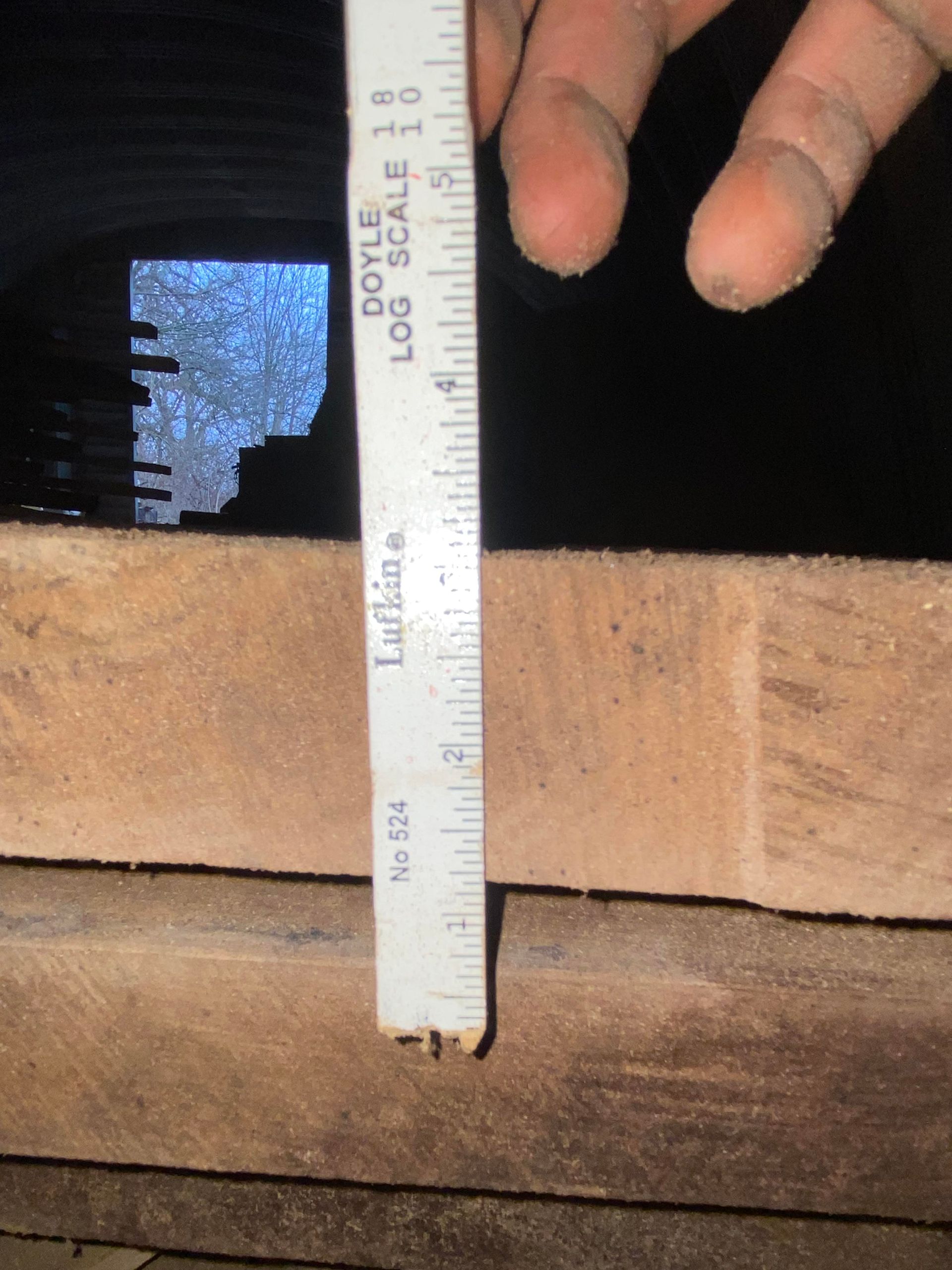 A ruler held over a wooden surface, showing a measurement of approximately 1 inch.