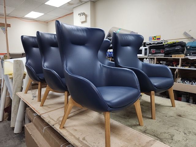 A row of blue leather chairs are sitting on top of a wooden table.
