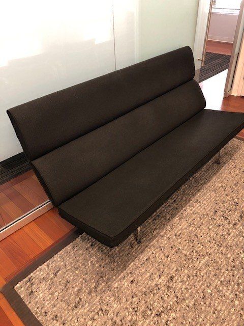 A black couch is sitting on a rug in a room