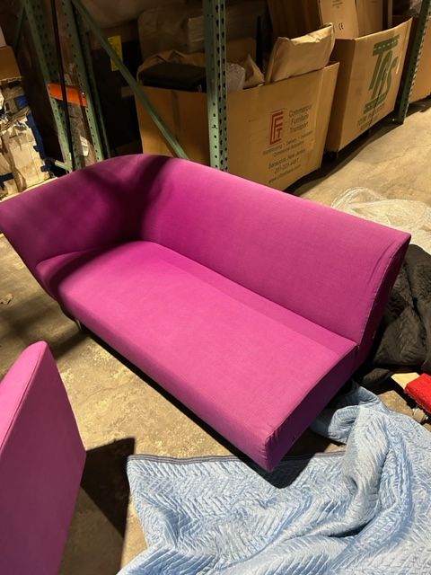 A purple couch is sitting on a blue blanket in a warehouse