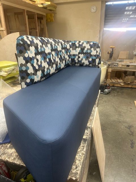 A blue couch is sitting on top of a wooden table in a room.