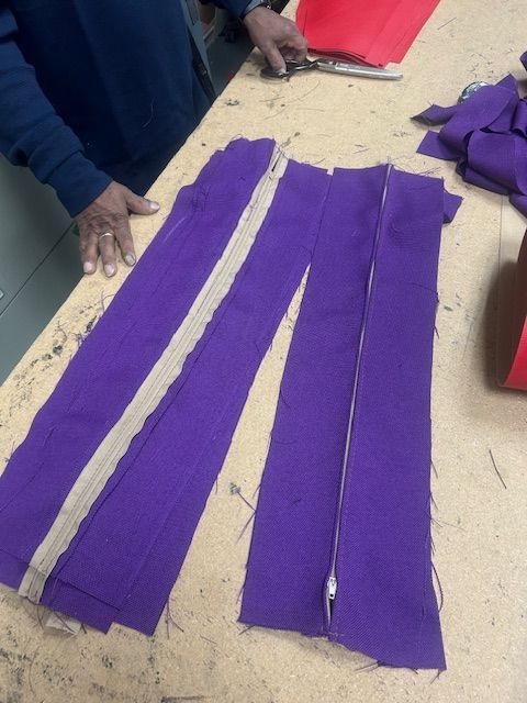 A person is cutting purple fabric on a table