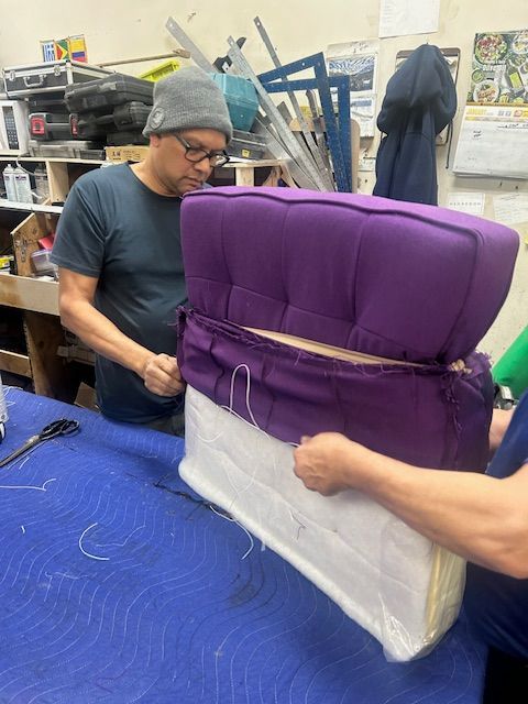 A man and a woman are working on a purple chair