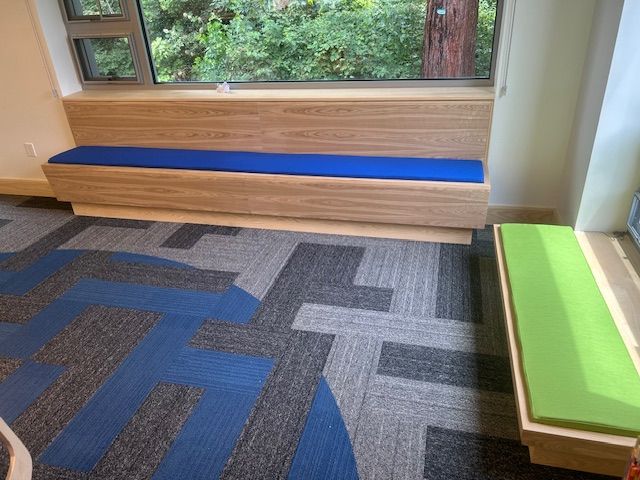 A room with a blue bench and a green bench in front of a window.