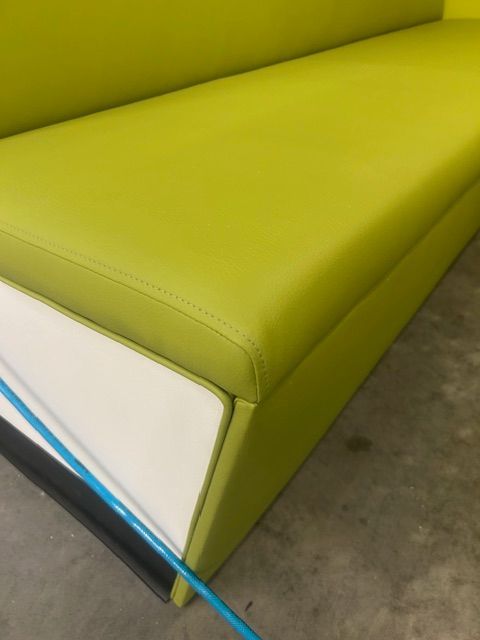 A green couch with a blue hose attached to it