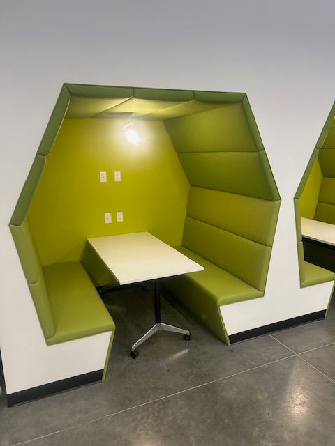 A green booth with a white table in it