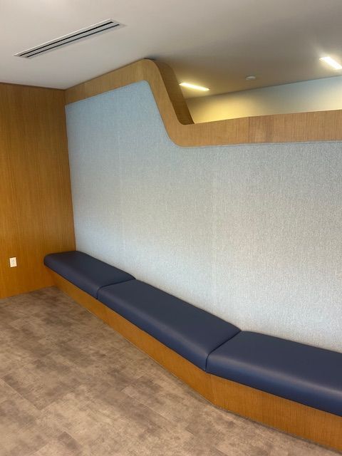 Built-in seating area with blue padded bench, light blue wall, and wood trim in a modern setting.
