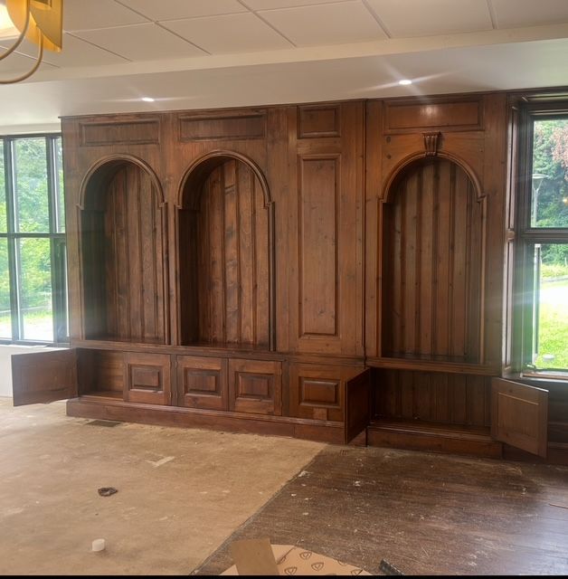 A dining room table is being painted in a room with a chandelier.