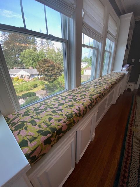 A window seat with a pink and green cushion