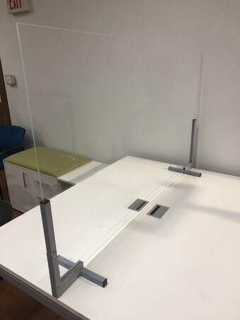 A clear acrylic divider is sitting on top of a white desk.