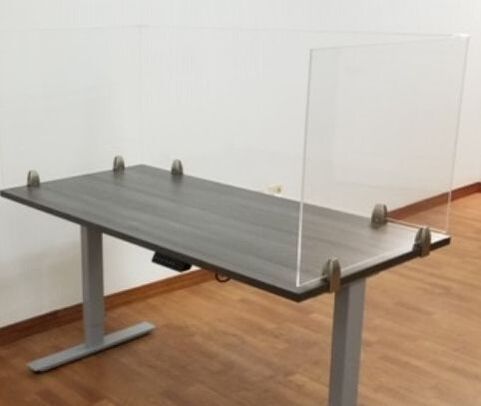 A standing desk with a clear acrylic divider attached to it.