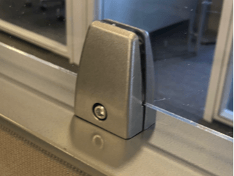 A close up of a sliding glass door with a metal clamp on it.