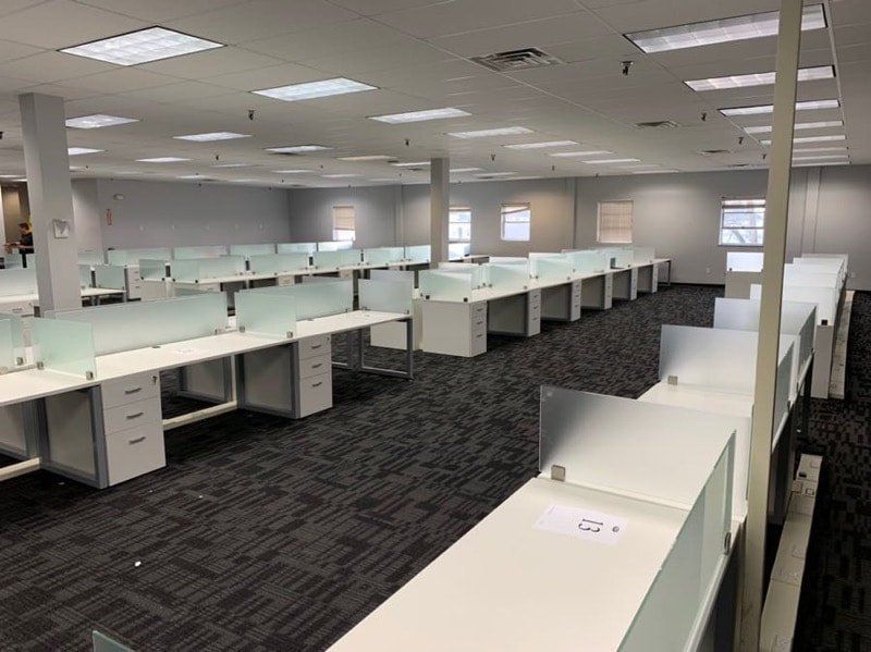 A large empty office with a lot of desks and cubicles.