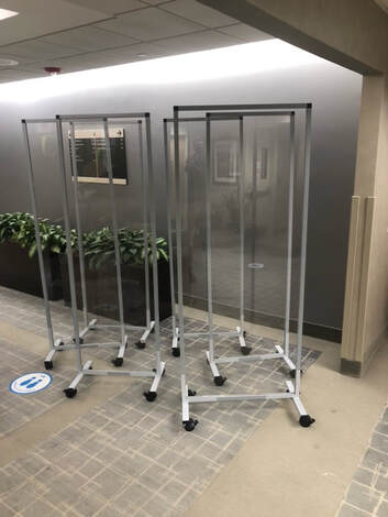 A bunch of clear dividers are sitting on the floor in a hallway.