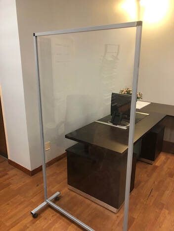 A clear divider is sitting in front of a desk in an office.