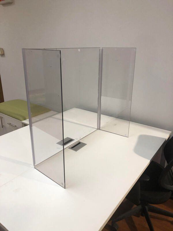 A clear acrylic divider is sitting on top of a white table.