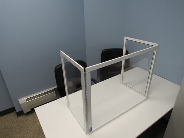 A white desk with a clear divider on it