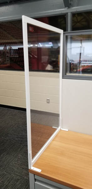 A clear plastic divider is sitting on top of a wooden desk.