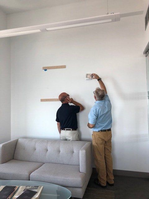 Two men are measuring a wall in a living room