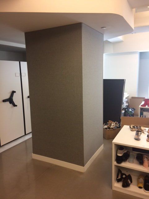 A room with a pillar and a shelf with shoes on it