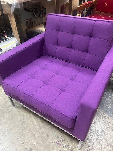 A purple couch is sitting on a concrete floor in a room.