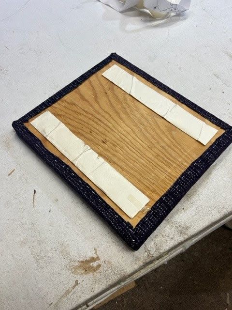 A piece of wood with two pieces of tape on it