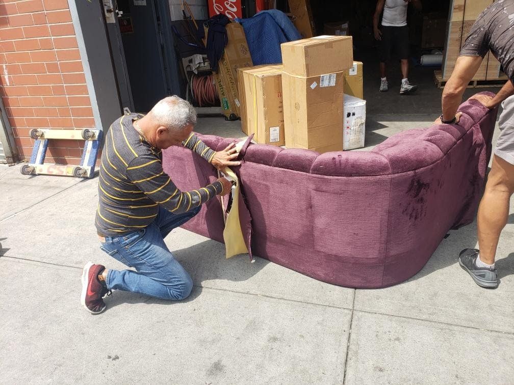 A man is kneeling down next to a purple couch.