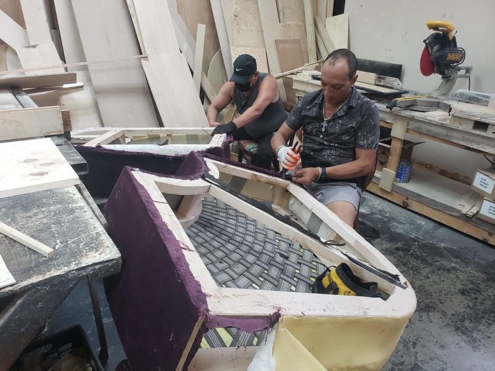 Two men are working on a piece of furniture in a workshop