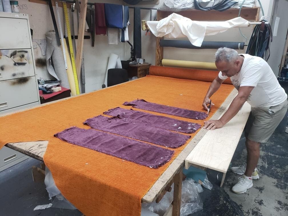 A man is cutting a piece of fabric on a table