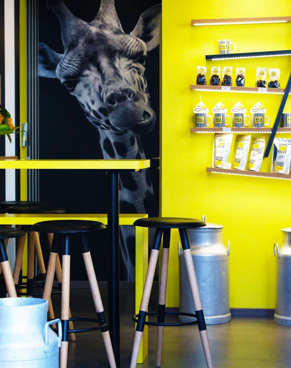 Détails d'un magasin Gagao avec assis haute; mur habillé avec une girafe et étagère originale pour les produits en vente additionnelle.