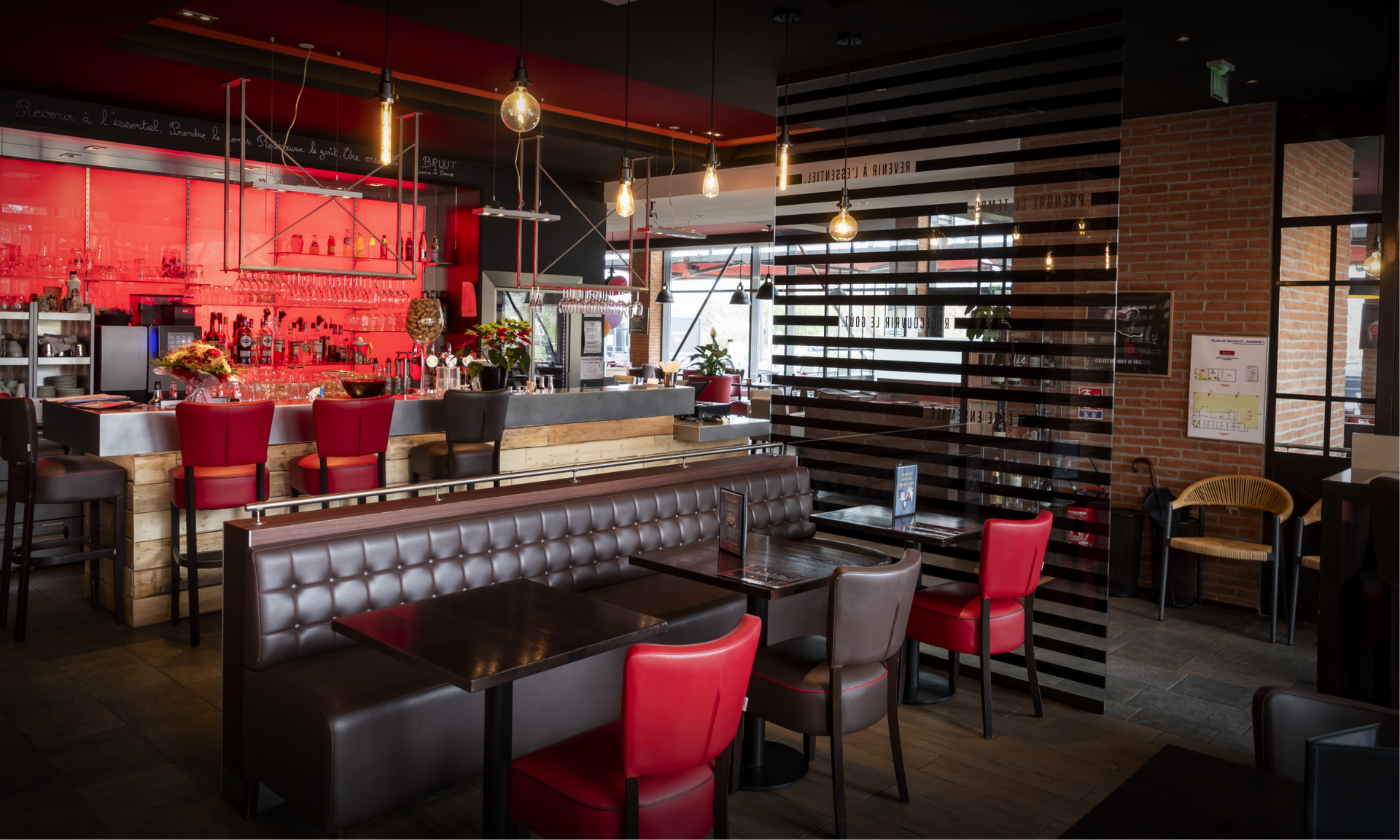 Intérieur de restaurant avec parquet, tables, chaises et une grand vitrage habillé.