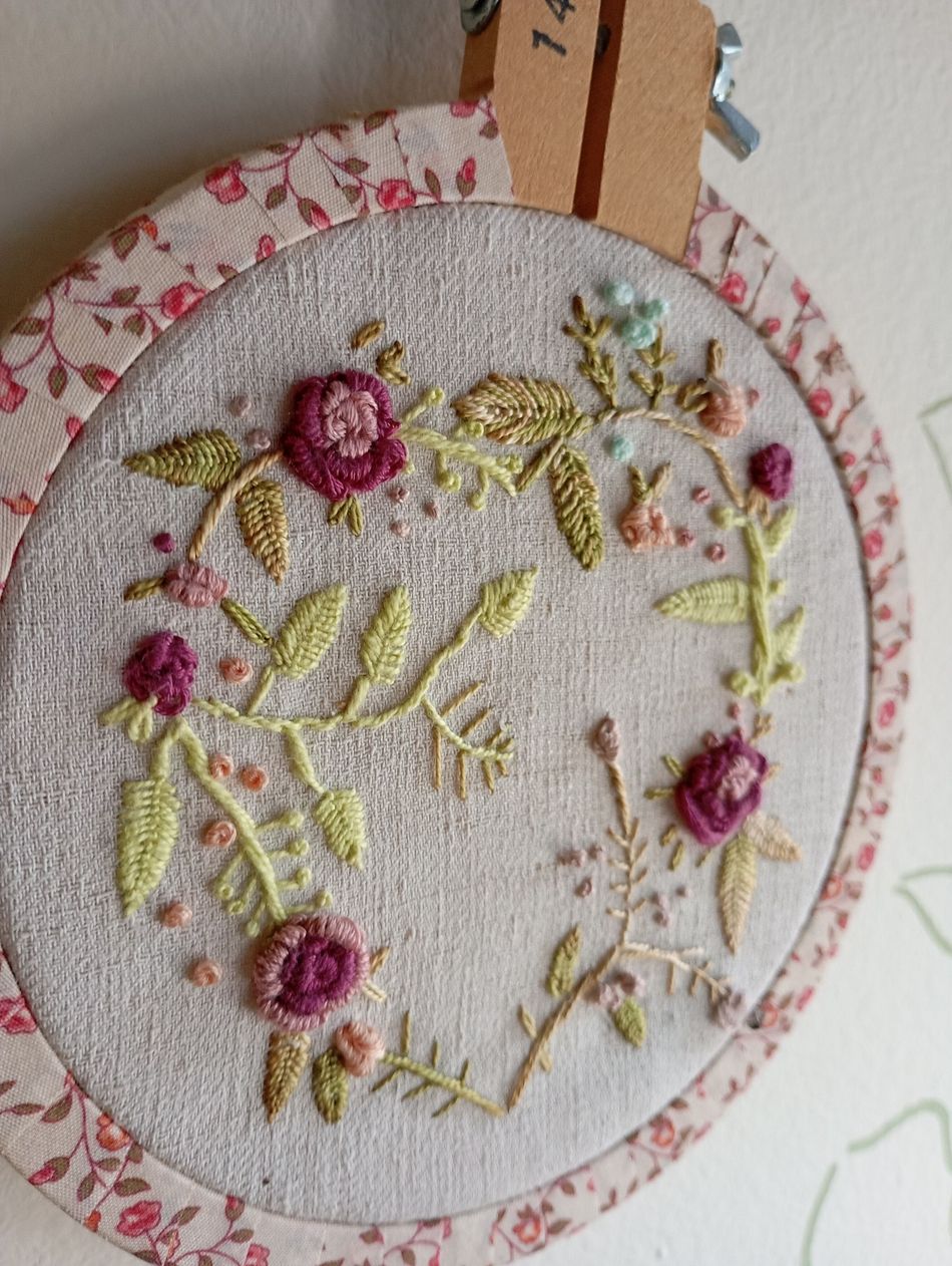 Dos chalecos de bebé de punto a rayas, uno rosa y otro verde, con pequeños parches en forma de corazón, sobre una mesa.