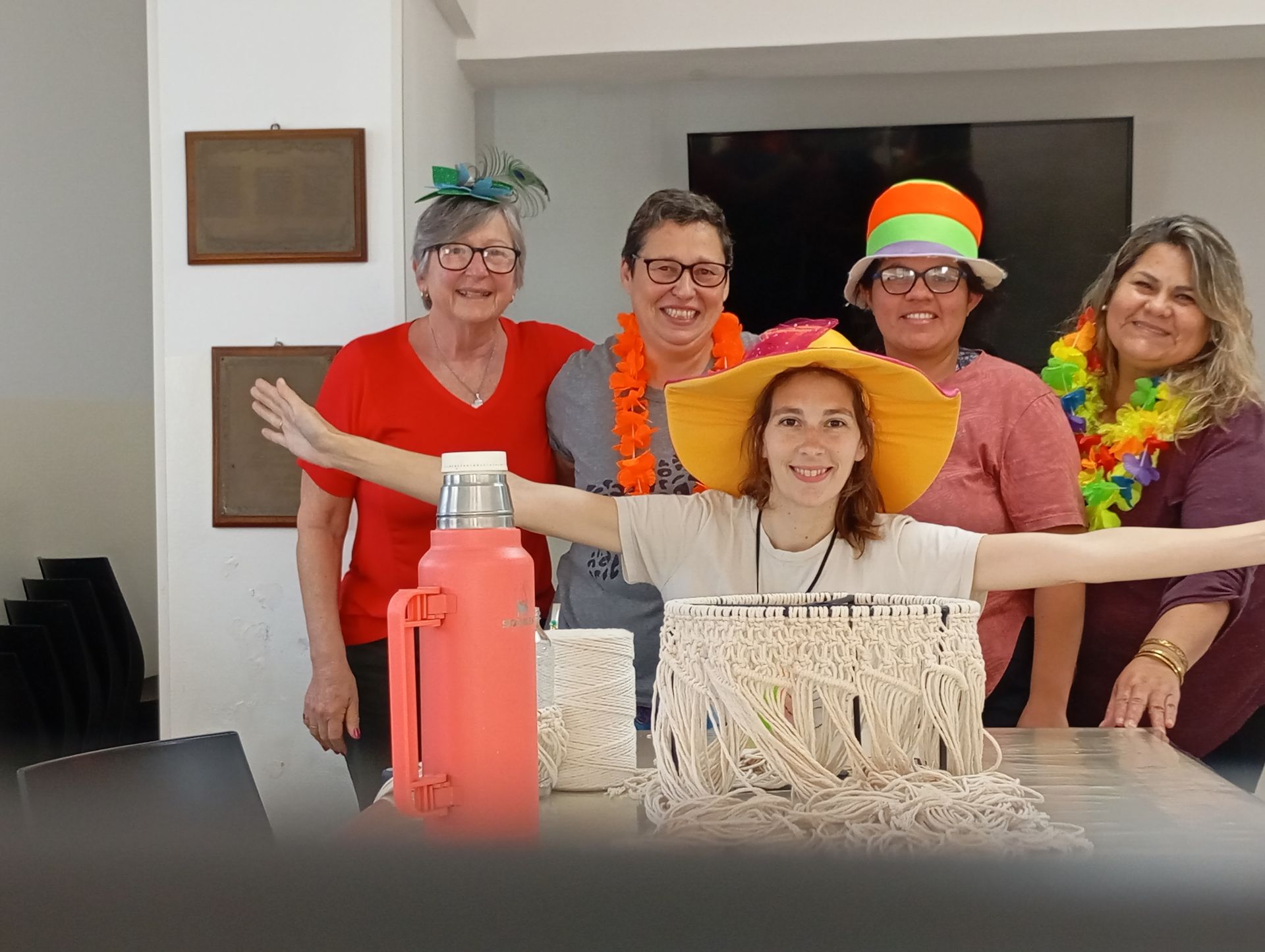 Grupo de cinco personas sonrientes posando detrás de una mesa con una botella de coral y un pequeño árbol decorativo blanco.