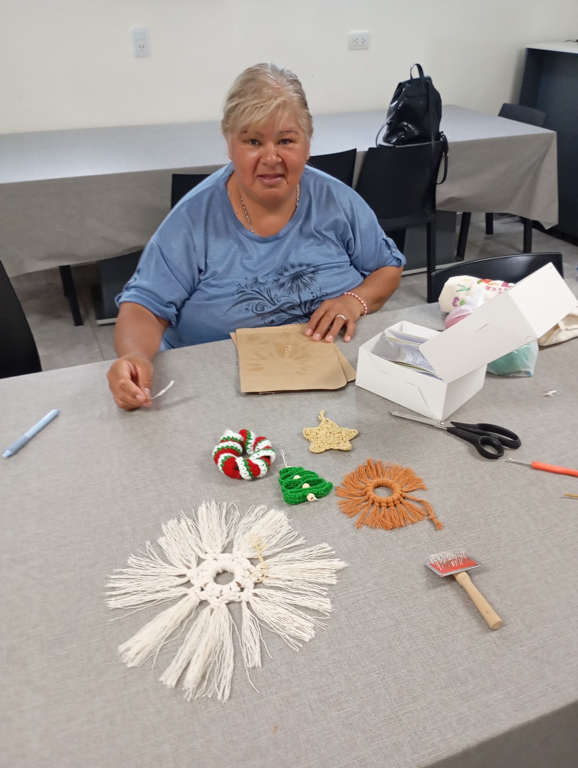 Una mujer sentada a una mesa con coloridas artesanías hechas a mano y una decoración de papel