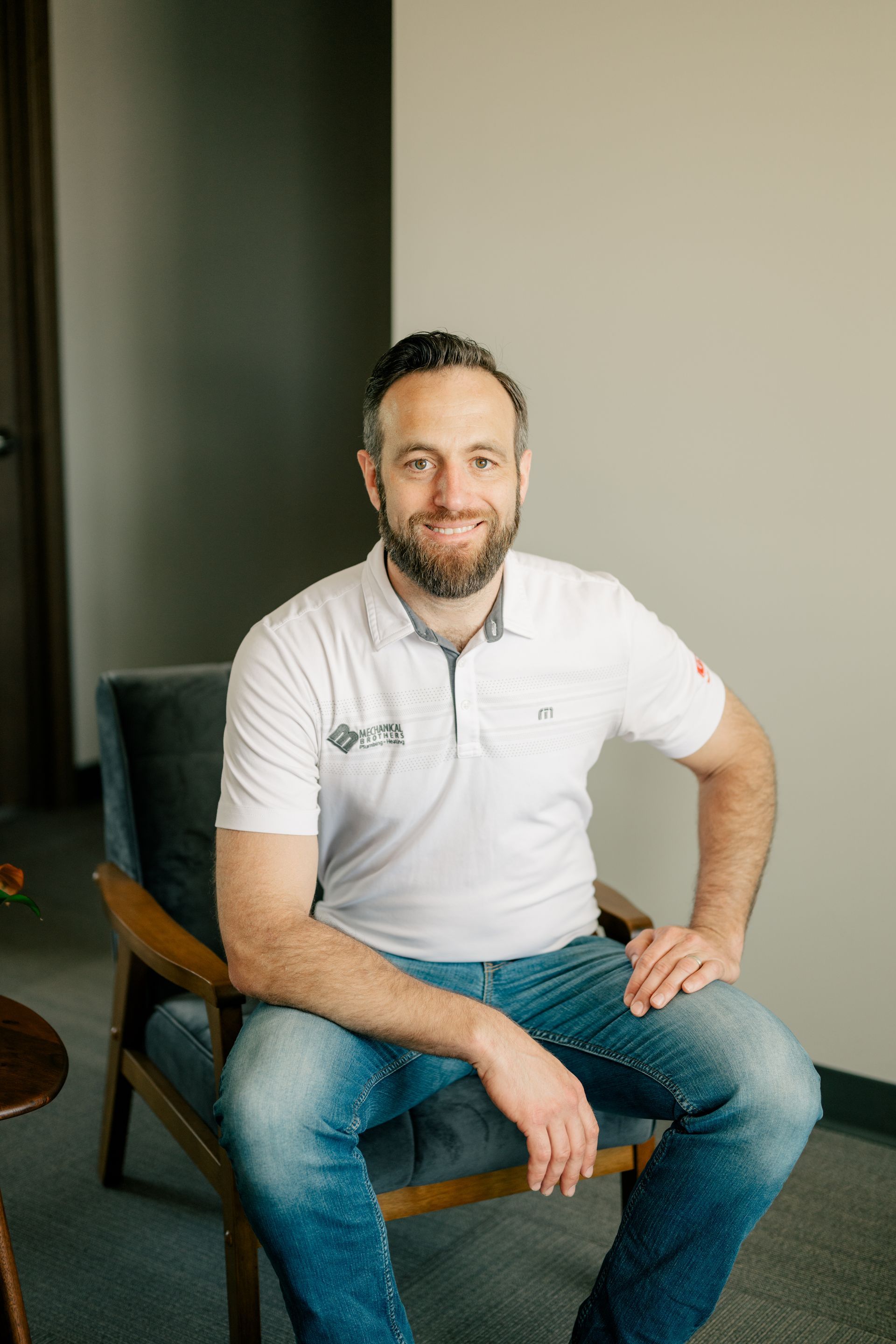 A man with a beard is sitting in a chair in a room.