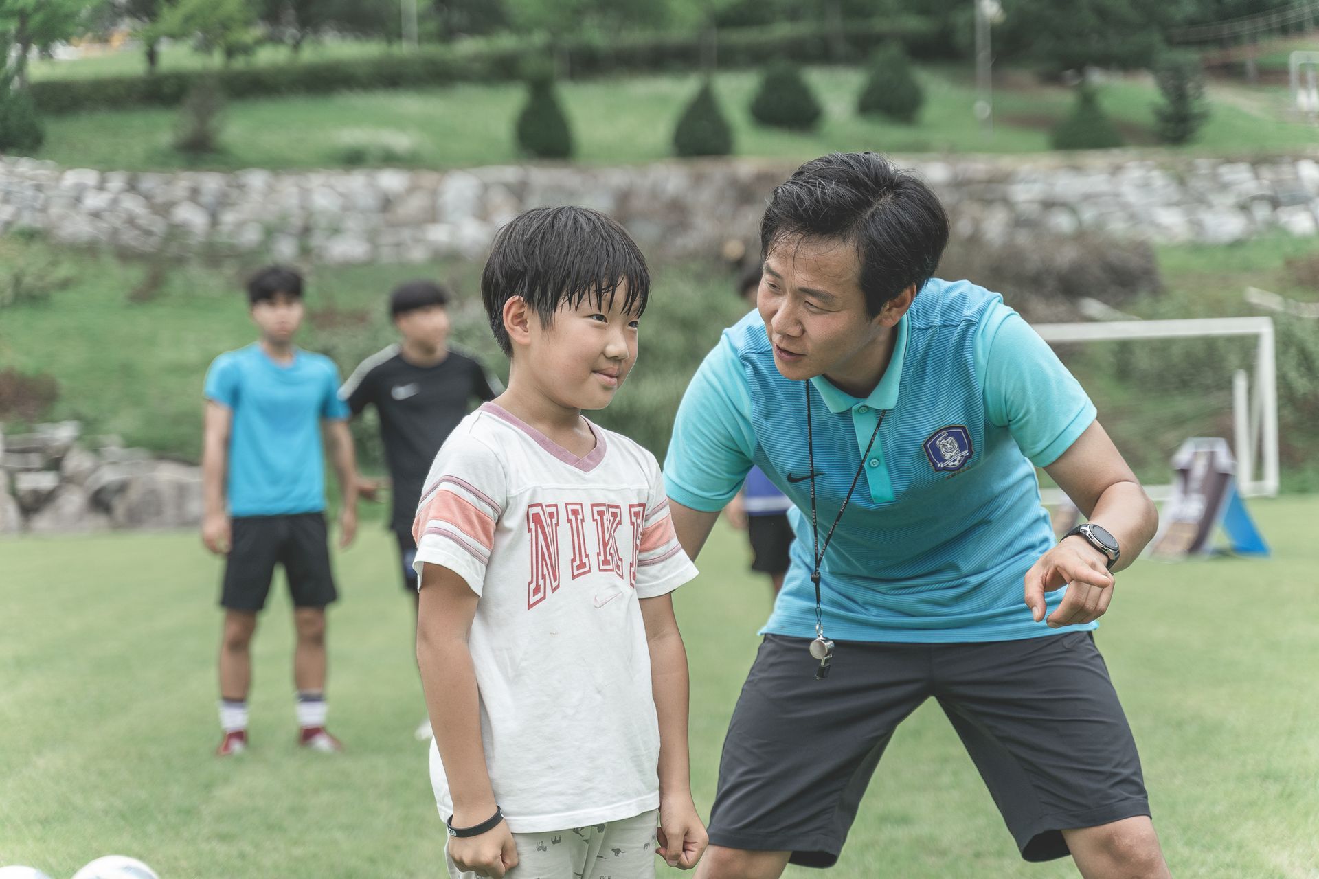 Two people on a grassy field, one coaching the other during a sports practice.