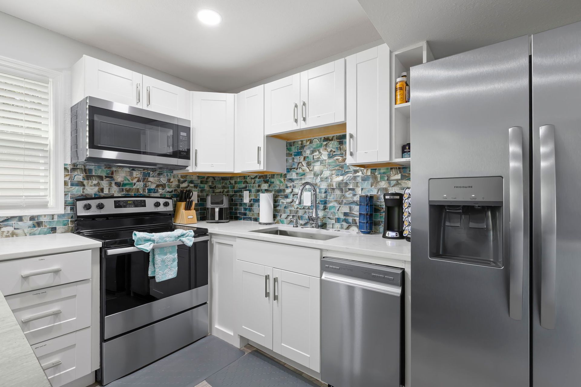 A kitchen with white cabinets , stainless steel appliances , a stove and a dishwasher.