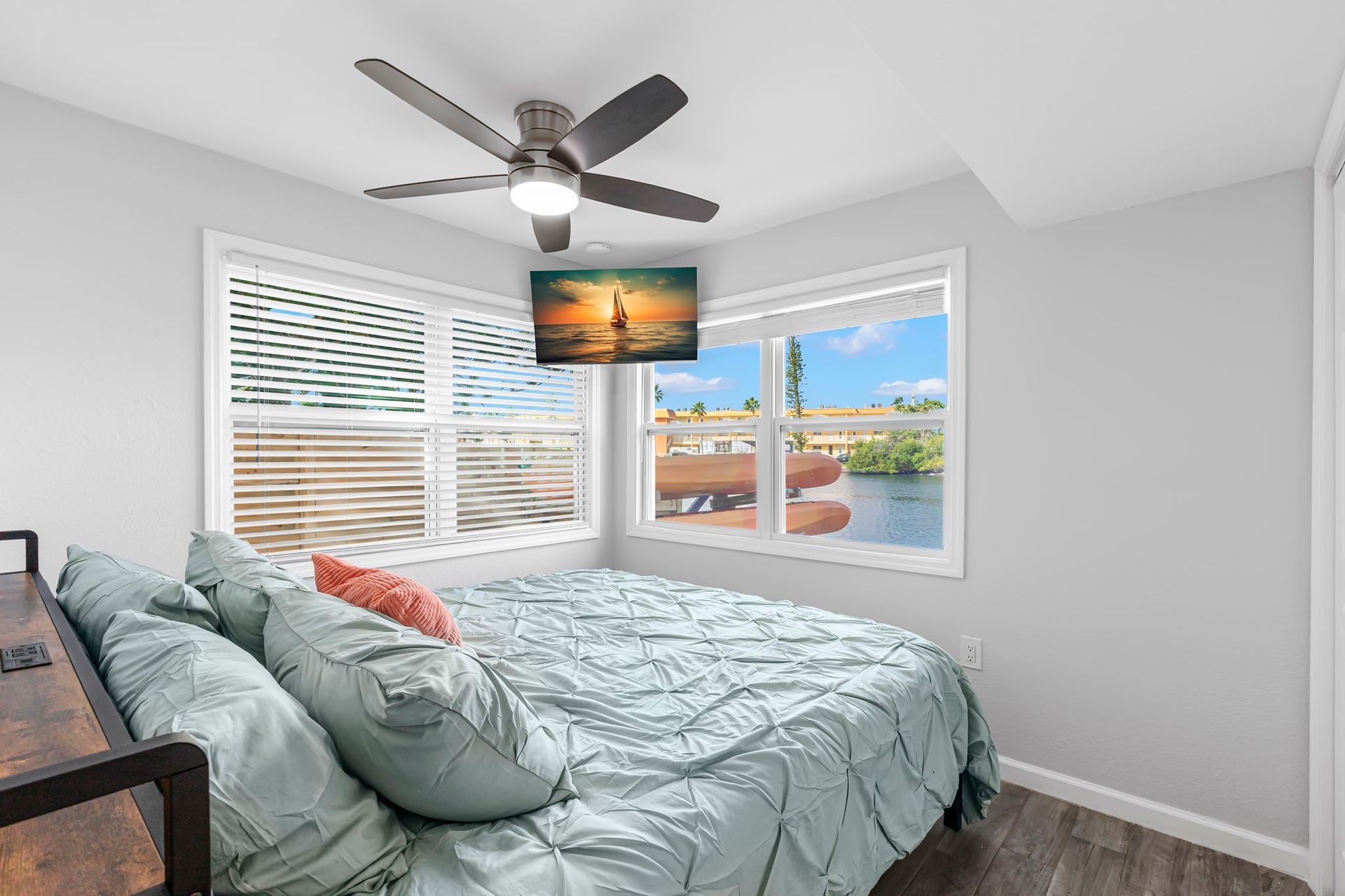 A bedroom with a bed , ceiling fan , television and sliding glass doors.