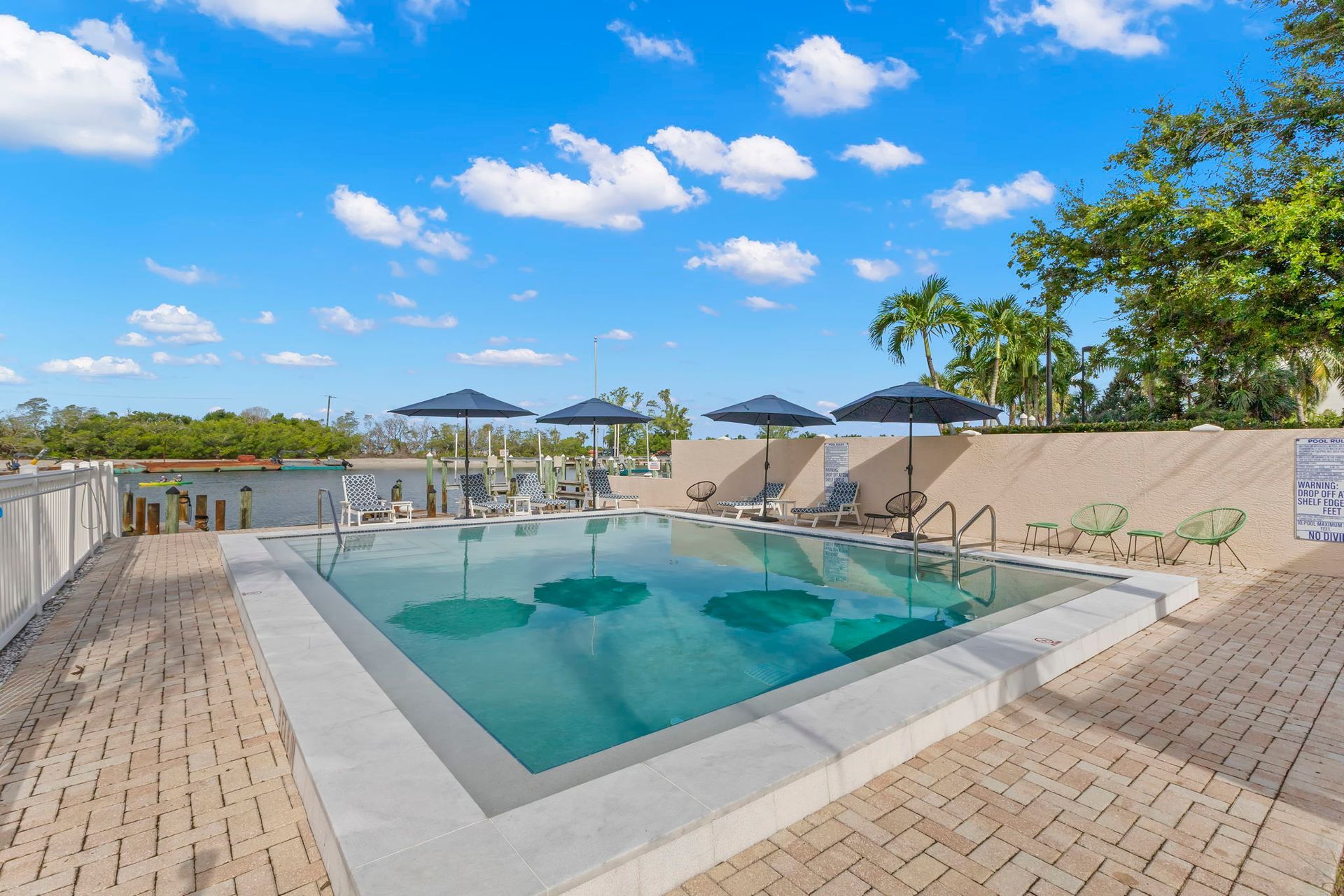 A large swimming pool surrounded by chairs and a fence