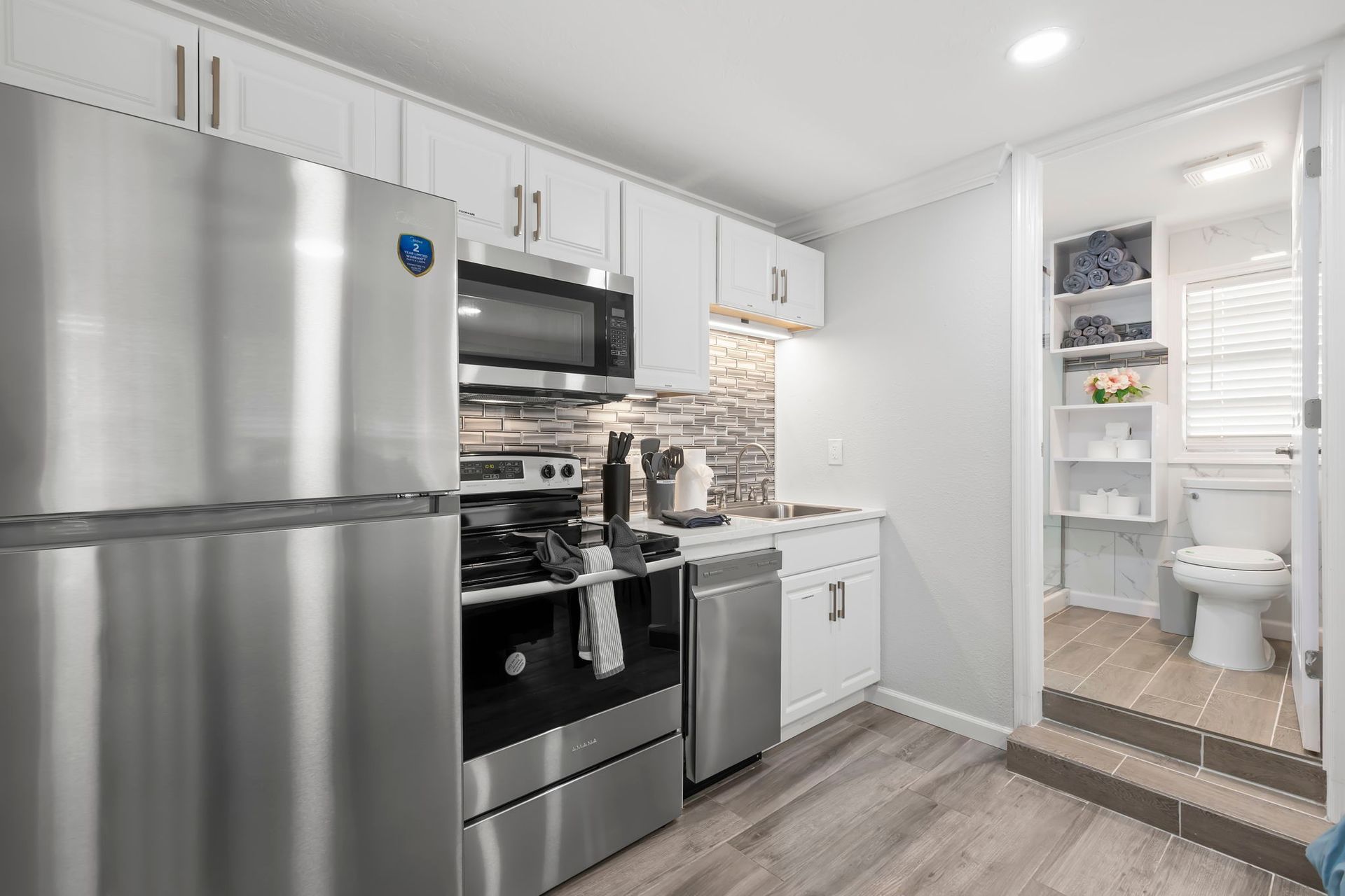 A kitchen with white cabinets , stainless steel appliances , a stove and a dishwasher.